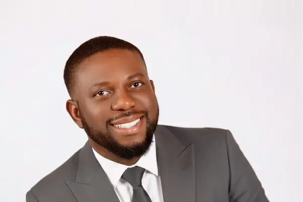 DK Shittu, Edmonton REALTOR® with LPT Realty, smiling in a grey suit and tie