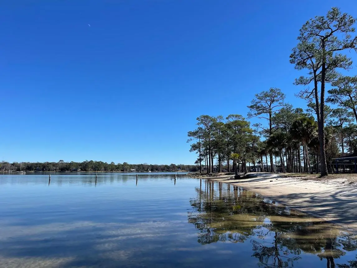Lincoln Park waterfront in Valparaiso, Florida, overlooking the calm waters of Boggy Bayou. Scenic Boggy Bayou shoreline with pine trees and waterfront views in Valparaiso, Florida.