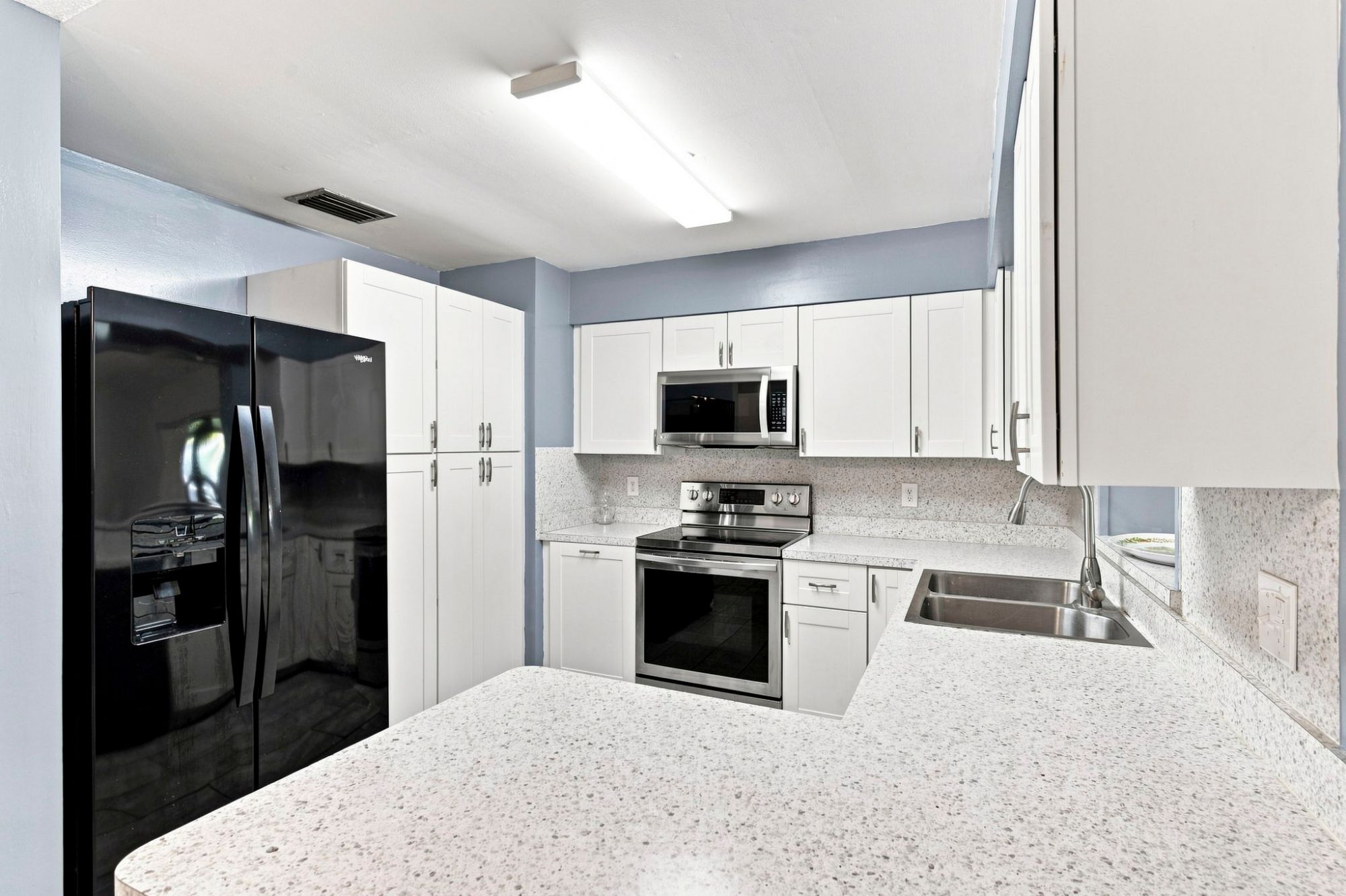 Updated kitchen with white shaker cabinets, stainless steel appliances and ample counter space