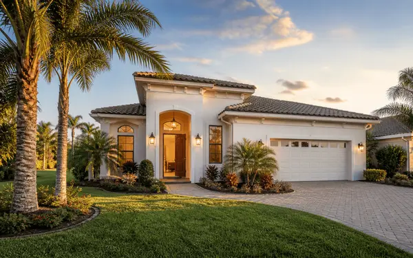 Central Florida single-family home at golden hour with palm trees and a paver driveway