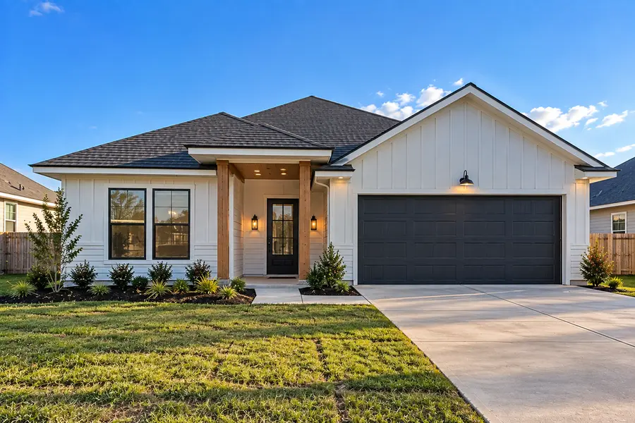 New construction white modern farmhouse with wood-trimmed front porch and a two-car garage