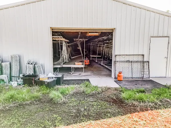 Powered, Climate-Controlled Warehouse, Viewed from West End nearest to road. Interior previous equipment seen includes grow tables; can be included with purchase upon discussion.