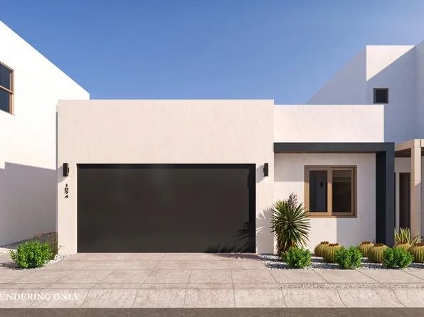 Contemporary Tucson home with a flat roof, smooth white stucco walls, a dark two car garage door, and minimal desert plantings along a concrete driveway.