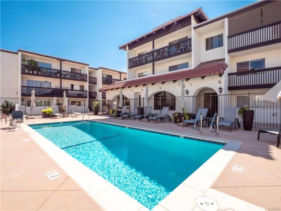 Encino Villas pool deck with lounge chairs, umbrellas and the building's balconies behind