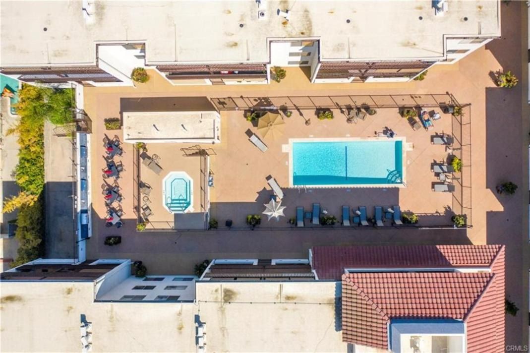 Aerial view of the Encino Villas courtyard with a rectangular pool, a separate fenced spa, lounge chairs and a covered seating area between the residential wings