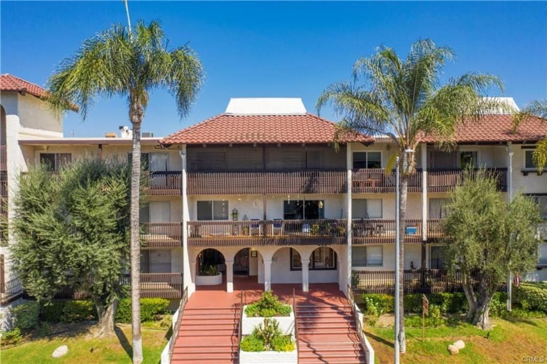 Front of Encino Villas at 5334 Lindley Avenue, Encino, a three-story Spanish-style condominium building with red tile roofs, balconies and twin entry stairs
