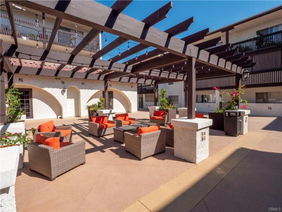 Covered courtyard lounge at Encino Villas with wicker seating under a wood pergola