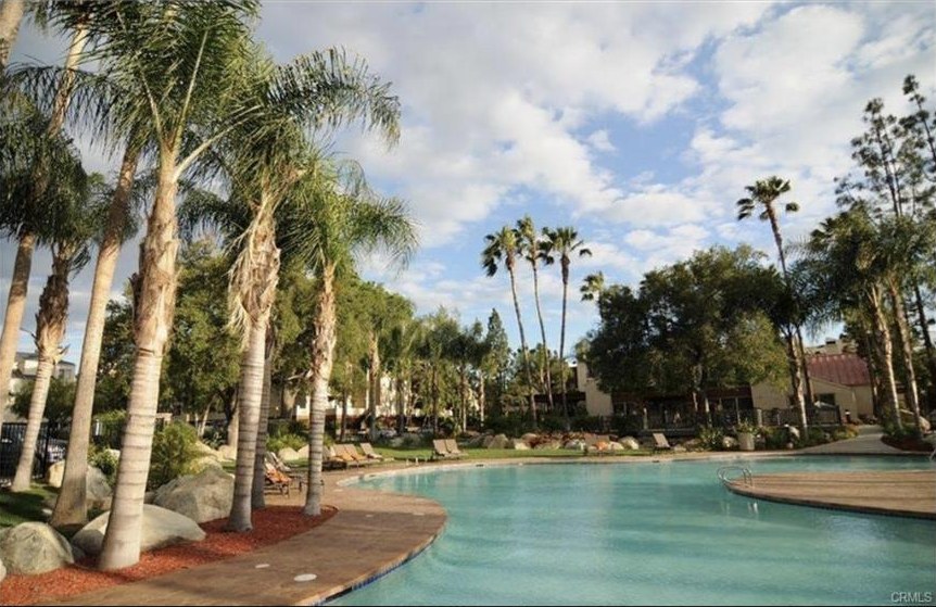 Resort-style swimming pool surrounded by palm trees at The Met Warner Center