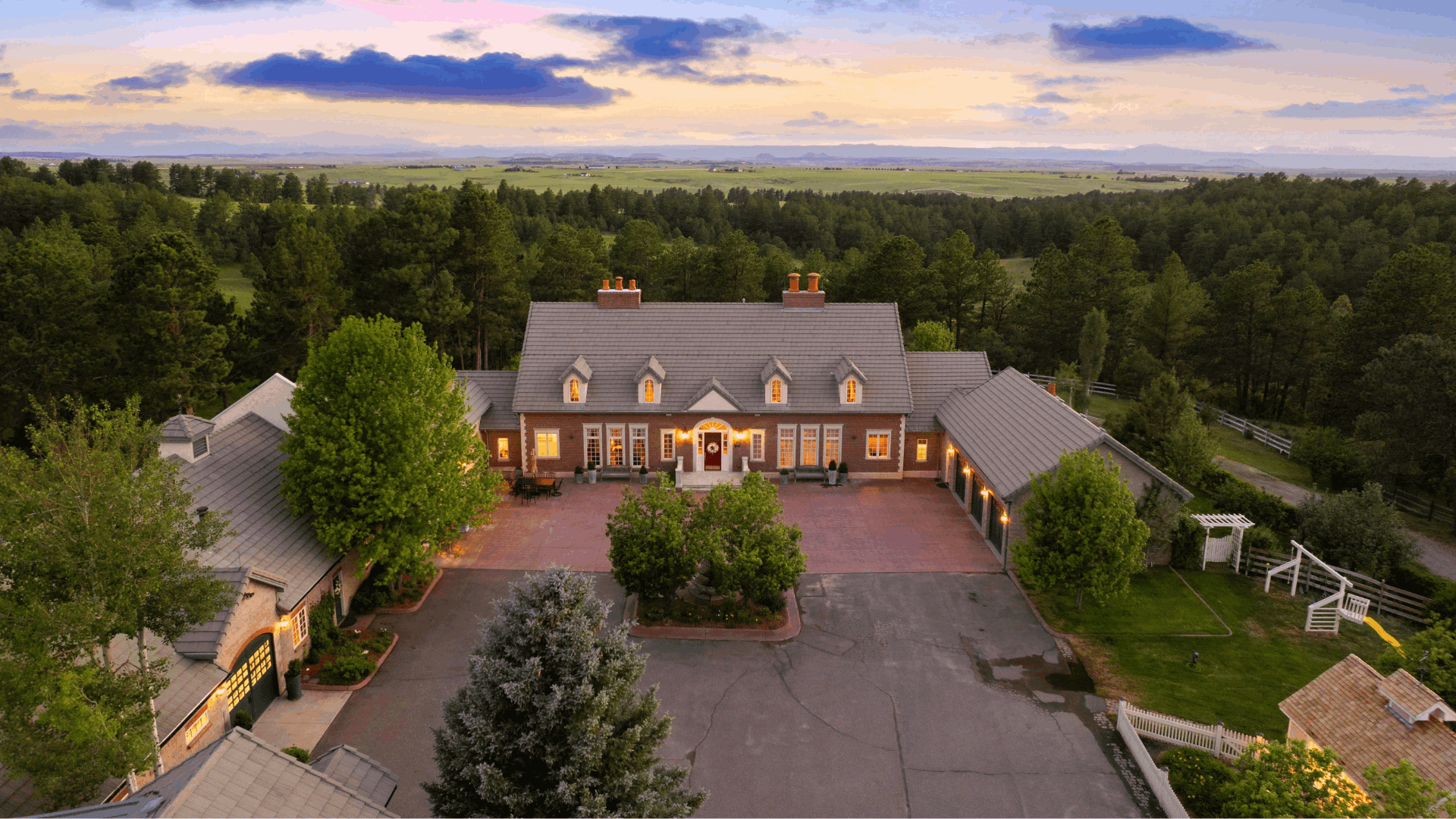 &ldquo;Aerial view of a luxury estate surrounded by trees and open fields in Colorado at sunset&rdquo;