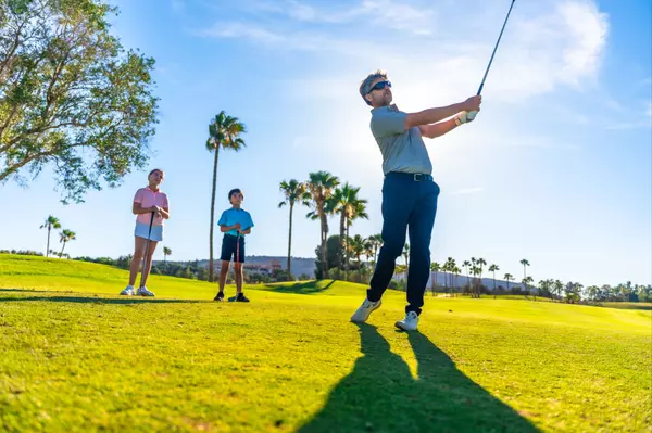 man-swinging-golf-while-teaching-to-two-children-2024-12-10-03-00-46-utc