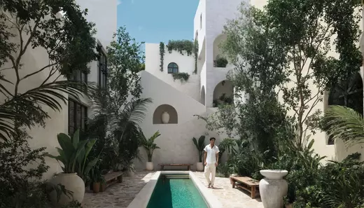 Luxury Mediterranean-style courtyard in Tulum featuring lush greenery, white stucco architecture, and a serene plunge pool.