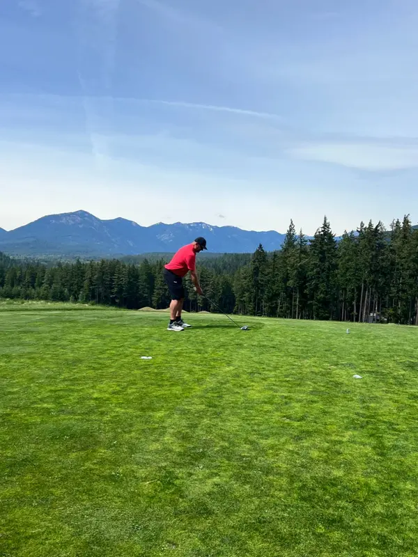 man in red with golf club in hand on green golf course