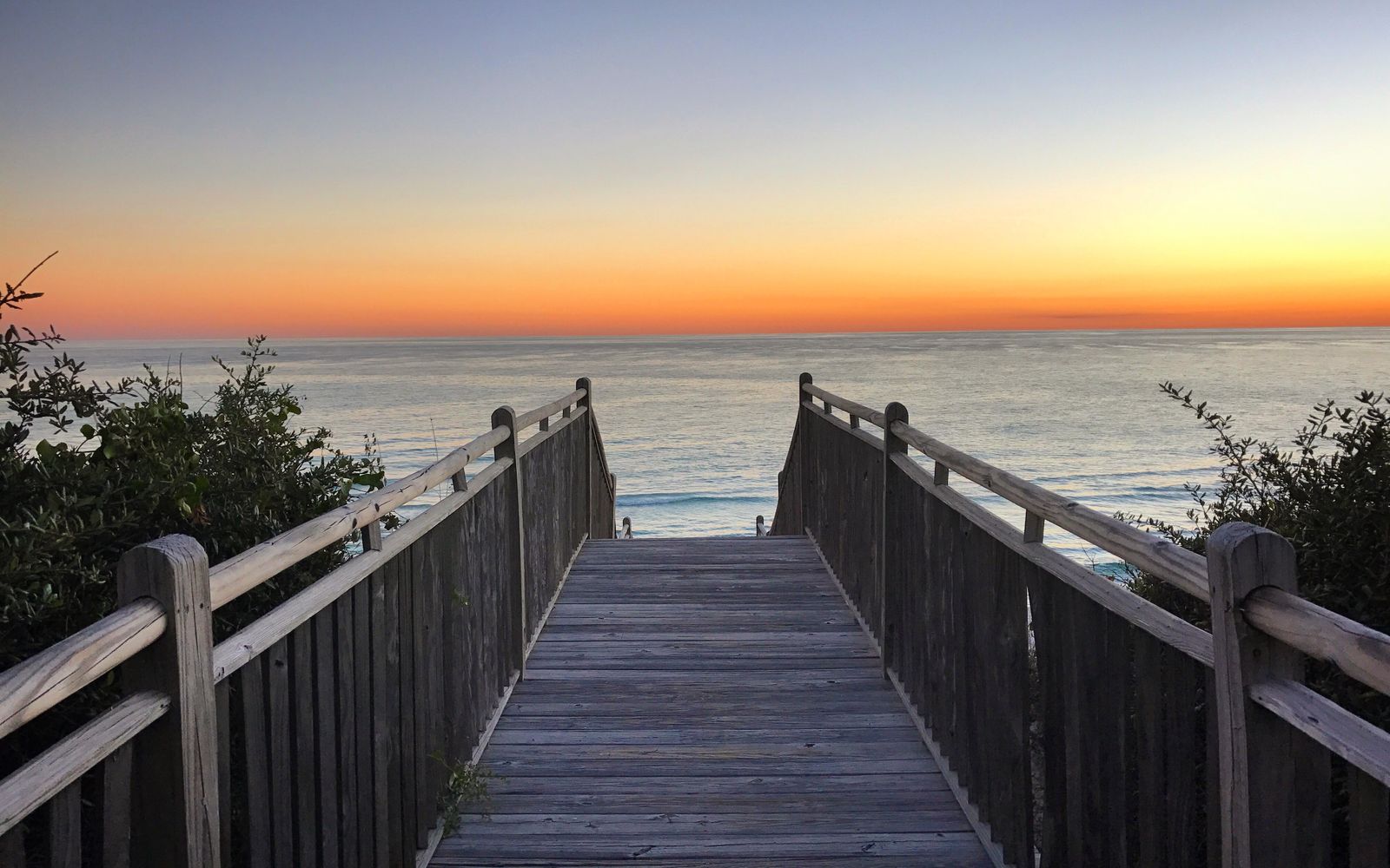 A wooden beach boardwalk leading to the ocean at sunset in Florida