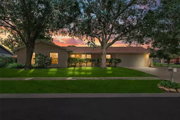Front view of 1807 Green Lawn Street showcasing beautiful curb appeal, manicured landscaping, and an elevated corner lot with a newer wood privacy fence.