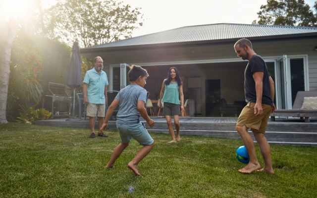 Family playing soccer in the backyard of a Disston Heights ranch home