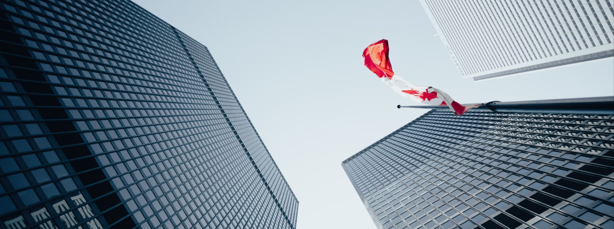 A Canadian flag outside modern office towers on the day of the Bank of Canada interest rate announcement