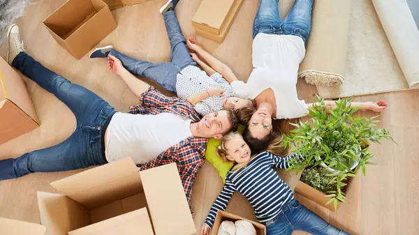 Happy family lying on floor among moving boxes after buying new home