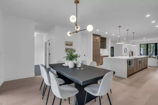 Modern open-concept dining area and kitchen with wood cabinetry, large island, and statement lighting.