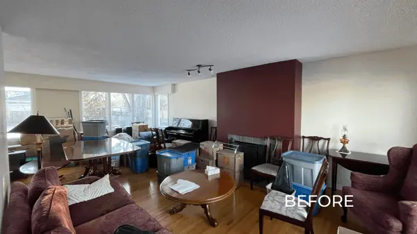 Living room in a Saskatoon home before staging, showing cluttered space with moving boxes, dark furniture, and outdated wall color