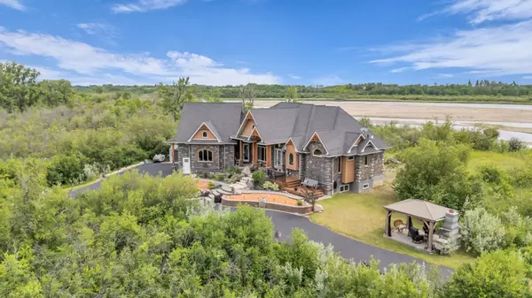 Aerial view of luxury custom home surrounded by trees with river in the background — Saskatoon real estate listing