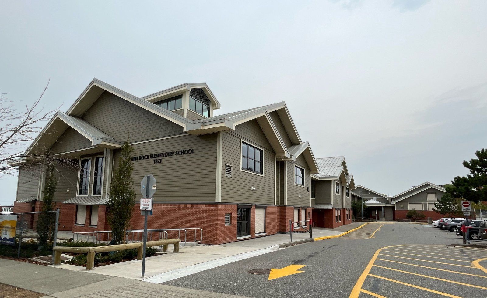 Modern glass and metal building of the Surrey School District Education Centre with landscaped greenery in front.