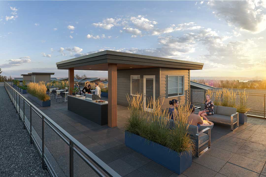 Inspire Maple Ridge rooftop amenity deck at sunset with outdoor kitchen, pergola, fire-pit seating, and Fraser Valley views