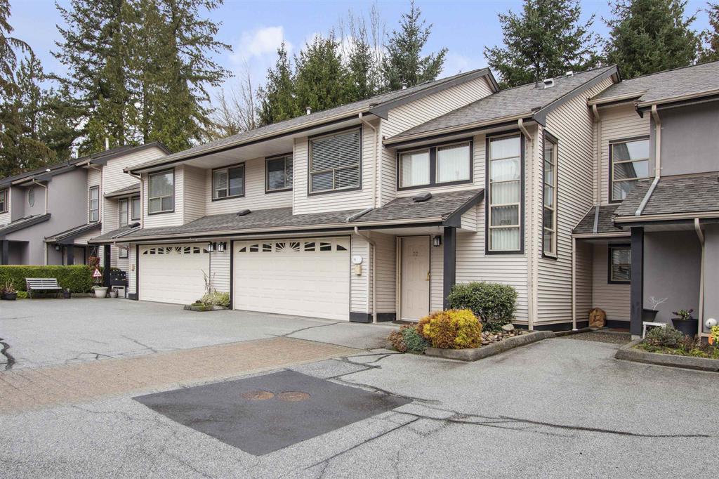 A row of older Maple Ridge townhomes with attached garages and mature landscaping in the complex