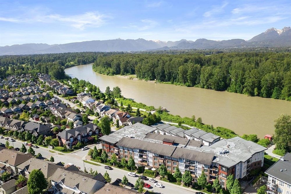 Aerial view of Fort Langley condos beside the Fraser River, with the mountains beyond