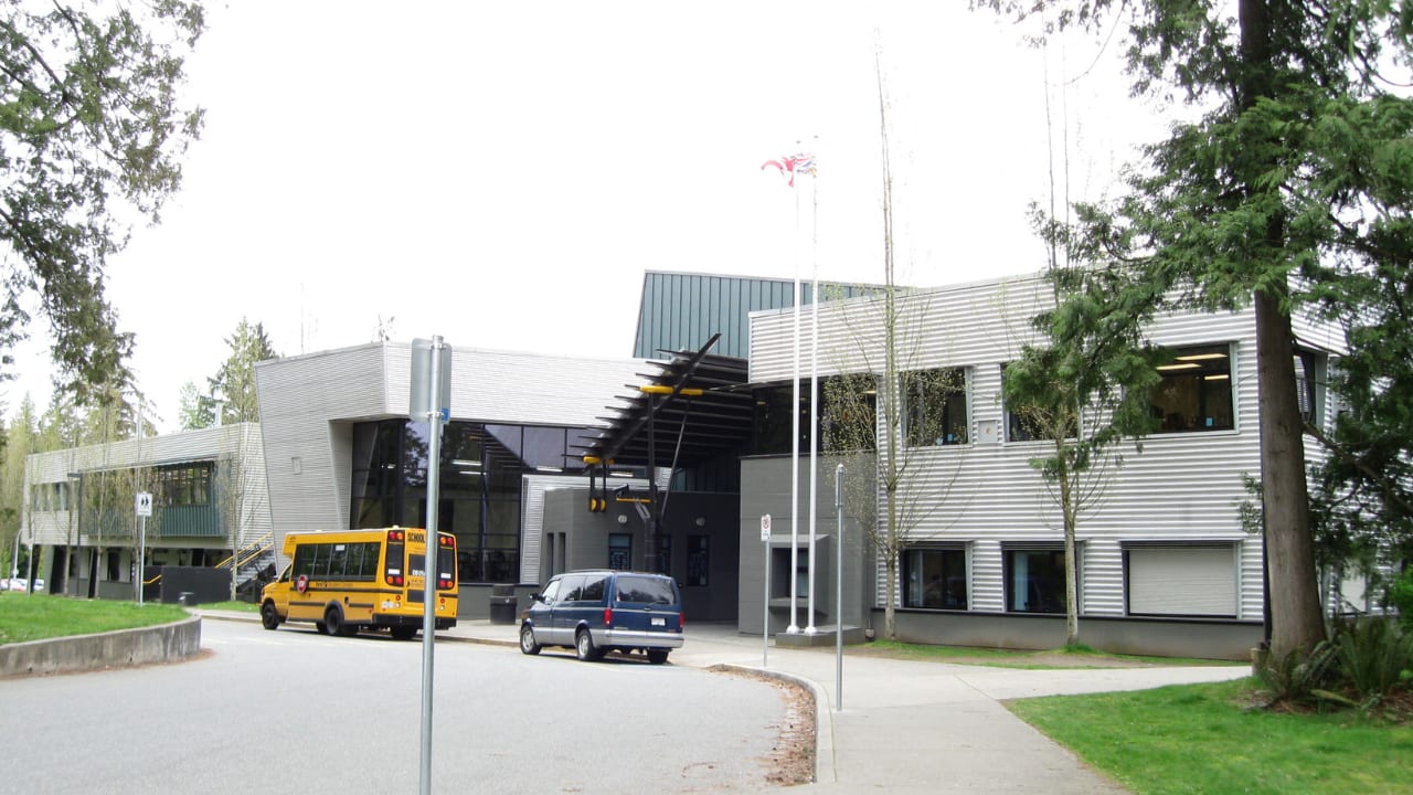 Main entrance of Fraser Heights Secondary with a school bus out front
