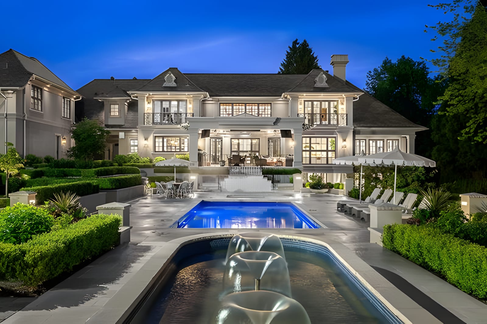 A large estate home with a pool at dusk in South Surrey