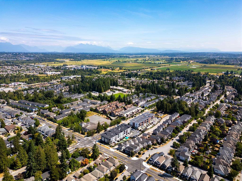 Aerial view over townhome and detached streets in Sullivan, Surrey, toward farmland and the mountains