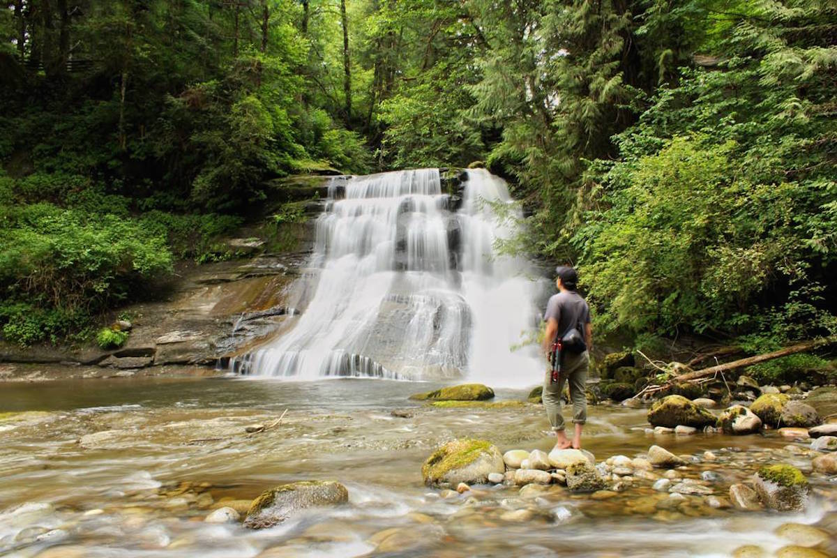 Cliff Falls in Kanaka Creek Regional Park, Maple Ridge, with a hiker on the rocks
