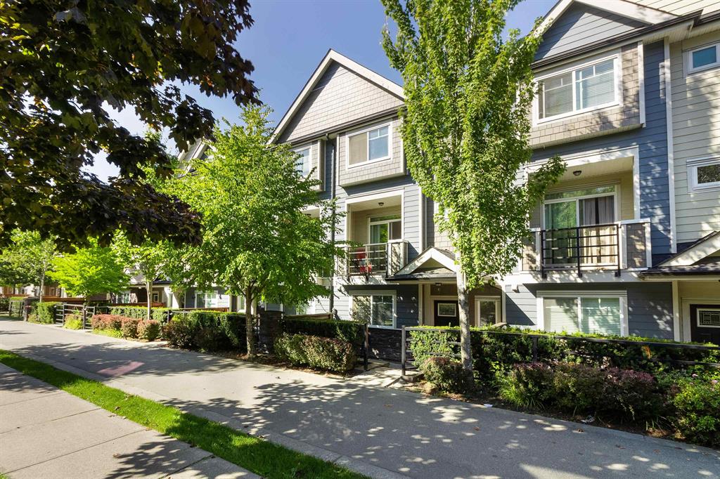 A row of 3-storey townhomes behind street trees in East Newton, Surrey
