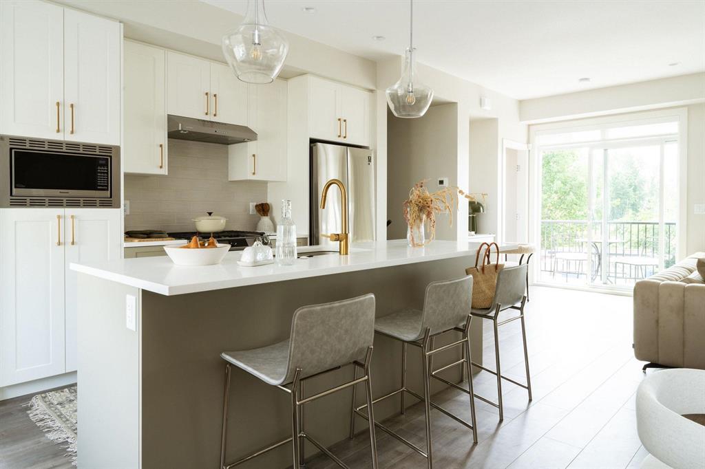 A kitchen with an island and pendant lights in a new South Surrey townhome