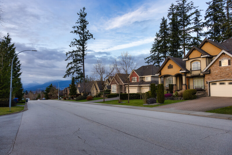 A street of large detached homes in Fraser Heights, Surrey, with mountains beyond