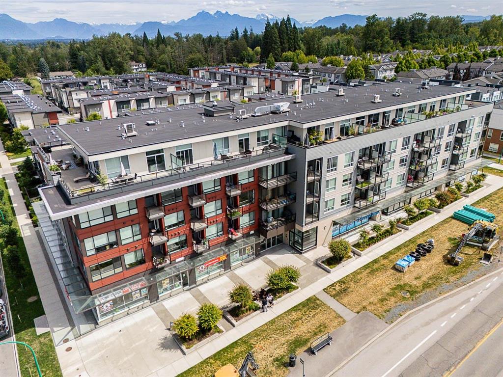 Aerial view of a 4-storey condo building in Clayton, Surrey, with the mountains beyond