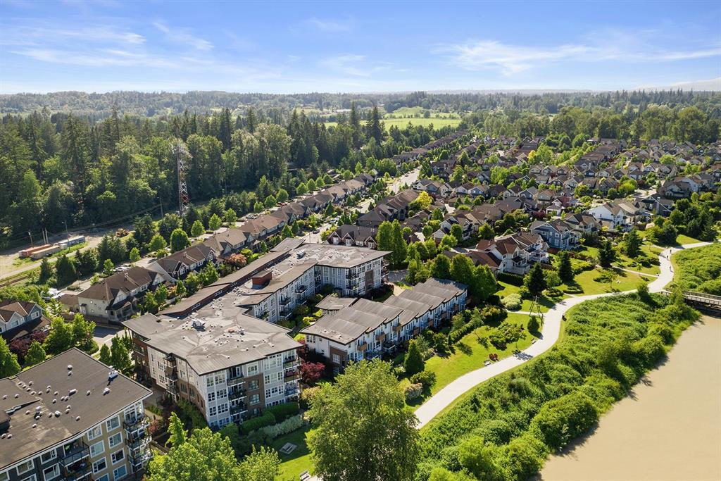 Aerial view of condos and townhomes beside a riverside trail and the Fraser River in Langley