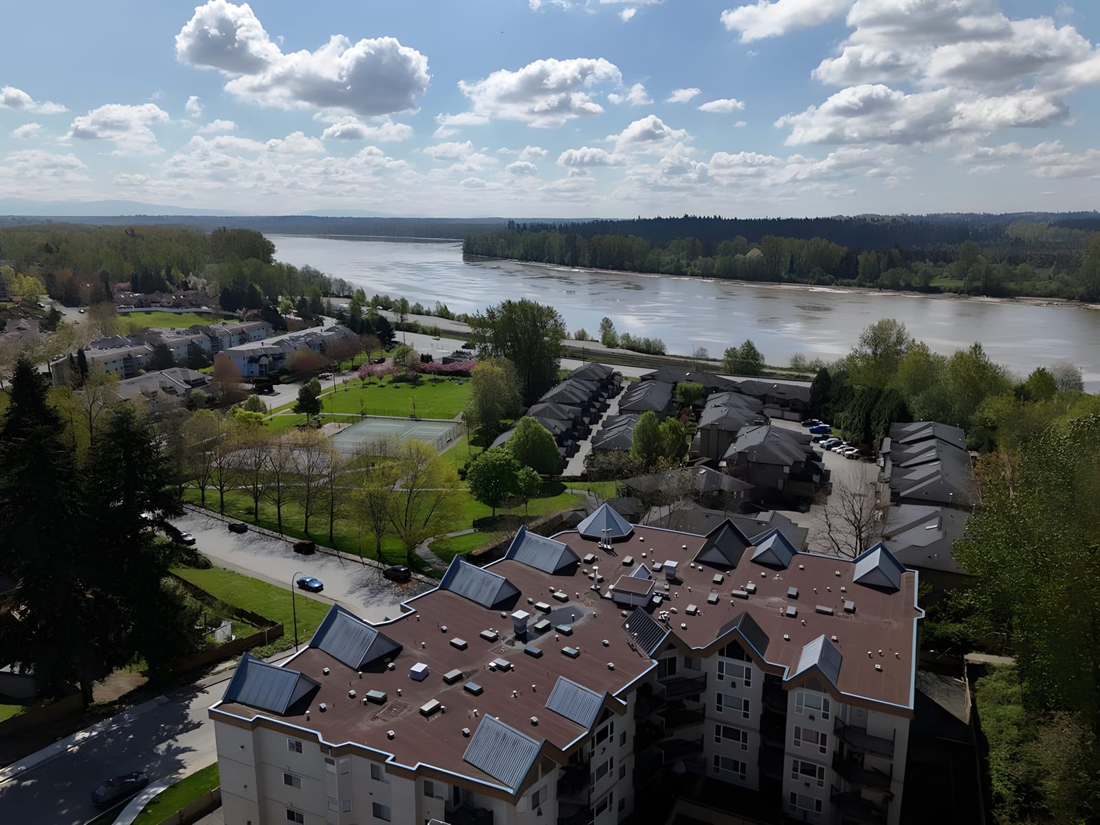 Aerial view of a condo building and townhomes beside the Fraser River in Maple Ridge
