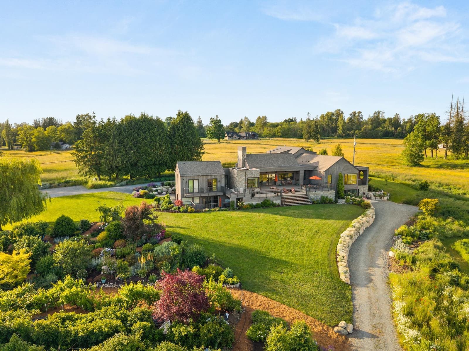 Aerial view of an acreage home with gardens and open fields in Langley