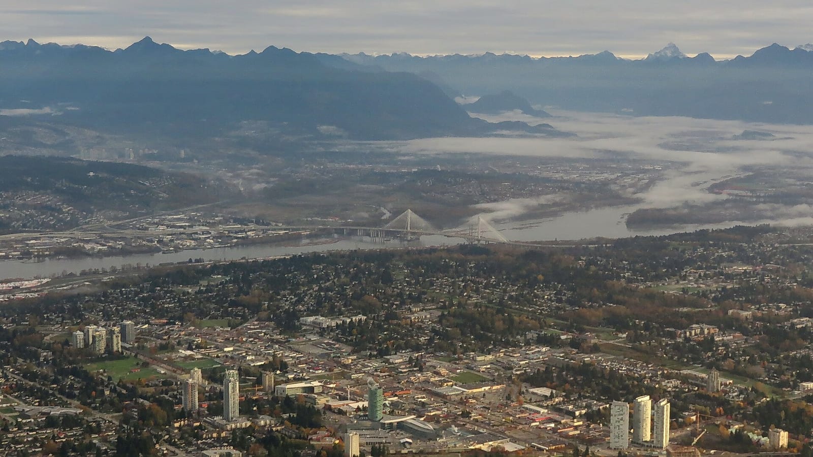 Aerial view of the Surrey Central towers, with the Fraser River and the Port Mann Bridge beyond