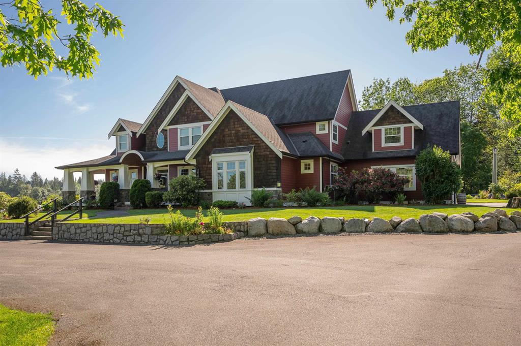 Acreage home with a wide paved drive near Fort Langley on a sunny day