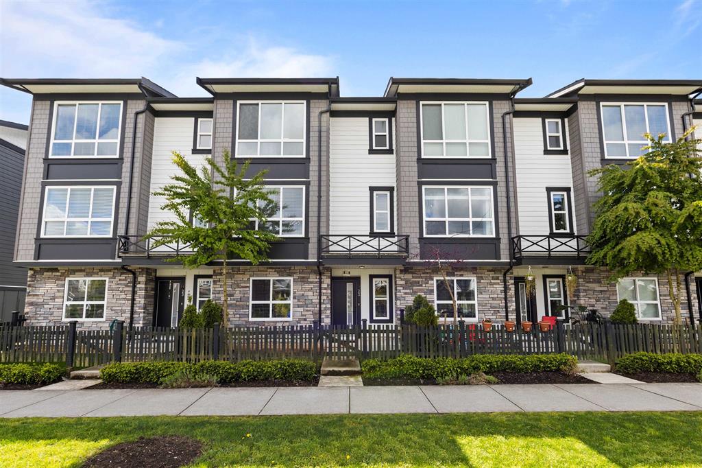 Three-storey townhouse row behind a picket fence in Clayton, Surrey
