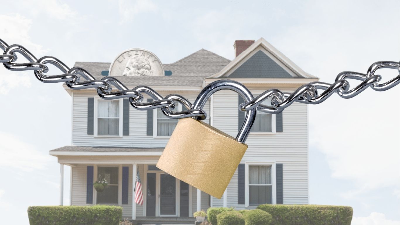 A home with a quarter going into the roof with a padlock across the front depicting locked up home equity