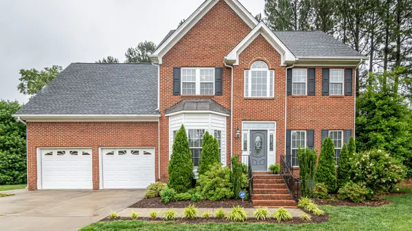 A two story brick family home with a wide driveway