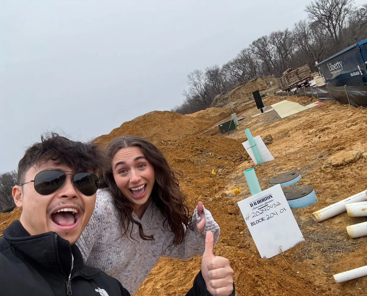 Anna and Nick at their new construction lot, beside the builder's stake