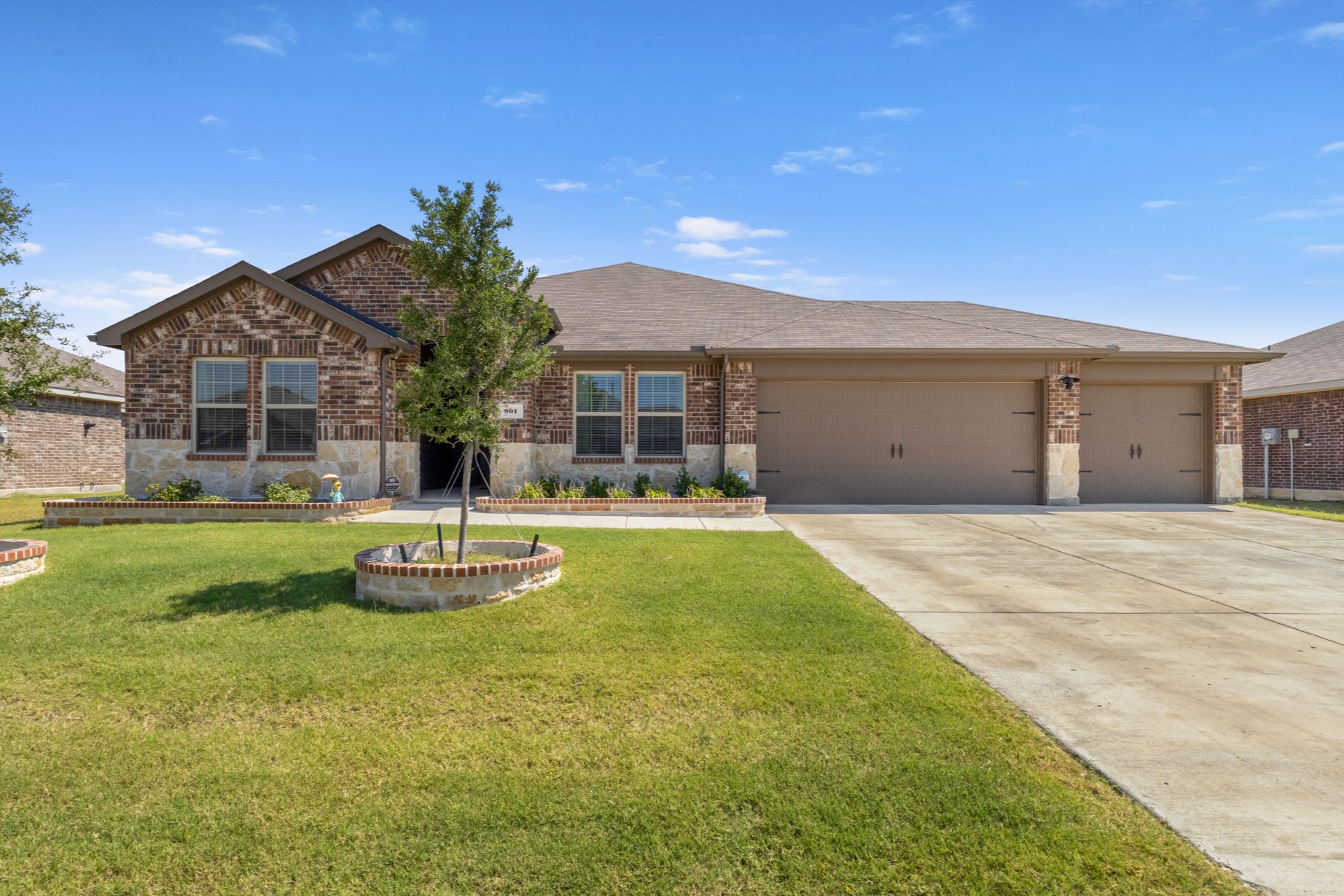 Front exterior of 901 Martingale Dr Josephine TX home for sale in Waverly Estates with stone-lined flower beds and 3-car garage.