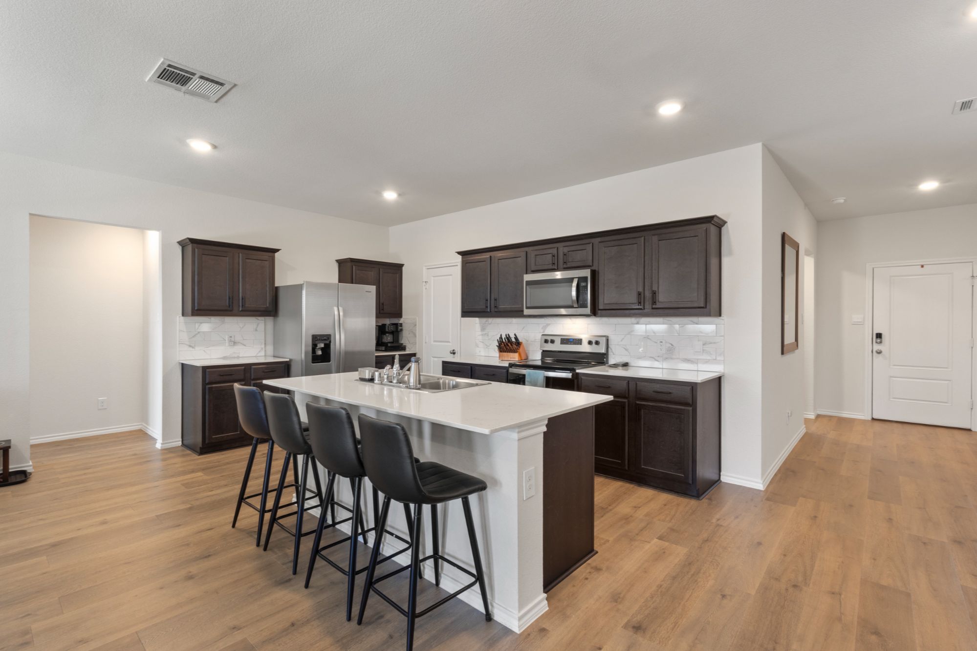 Modern kitchen in Waverly Estates Josephine TX with quartz countertops, stainless steel appliances, large island, and walk-in pantry.