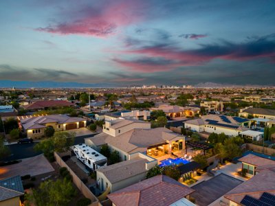 Aerial view of a Las Vegas valley neighborhood at sunset with the Strip skyline in the distance