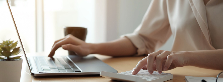Person using a calculator and a laptop to budget home buying costs, planning for hidden expenses