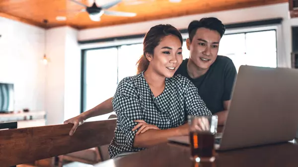 Smiling couple researching homes and working with a real estate agent online for relocation or referral support